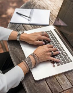person typing on MacBook Pro on brown wooden table during daytime photo